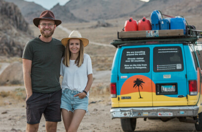 двойка на почивка позира за снимка, а до тях има пъстър автомобил с висока проходимост