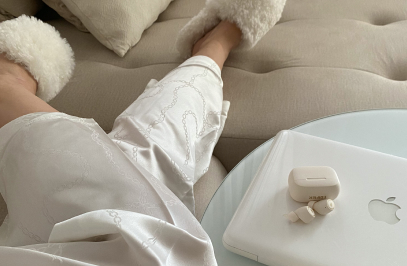 човек, който лежи на диван, а до него има лаптоп и калъф с безжични слушалки