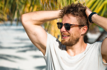 мъж със слънчеви очила, къси ръкави и под палми