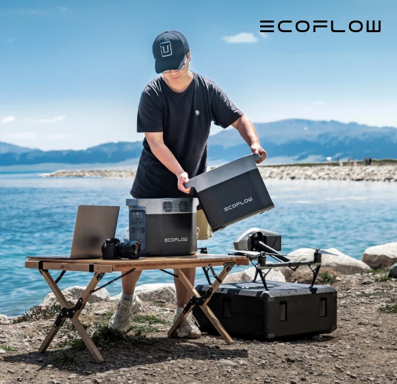 мъж на брега, до него маса и на нея електростанции