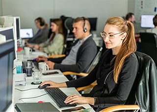 хората седят на бюрата си и работят.